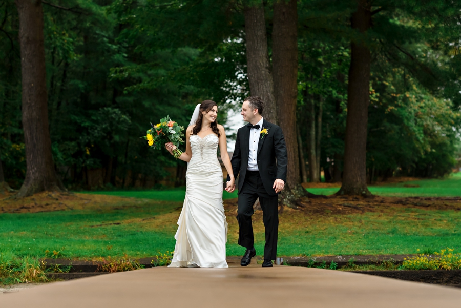 A man and woman walk along a dock after their wedding ceremony at Lake Bryn Mawr Camp.